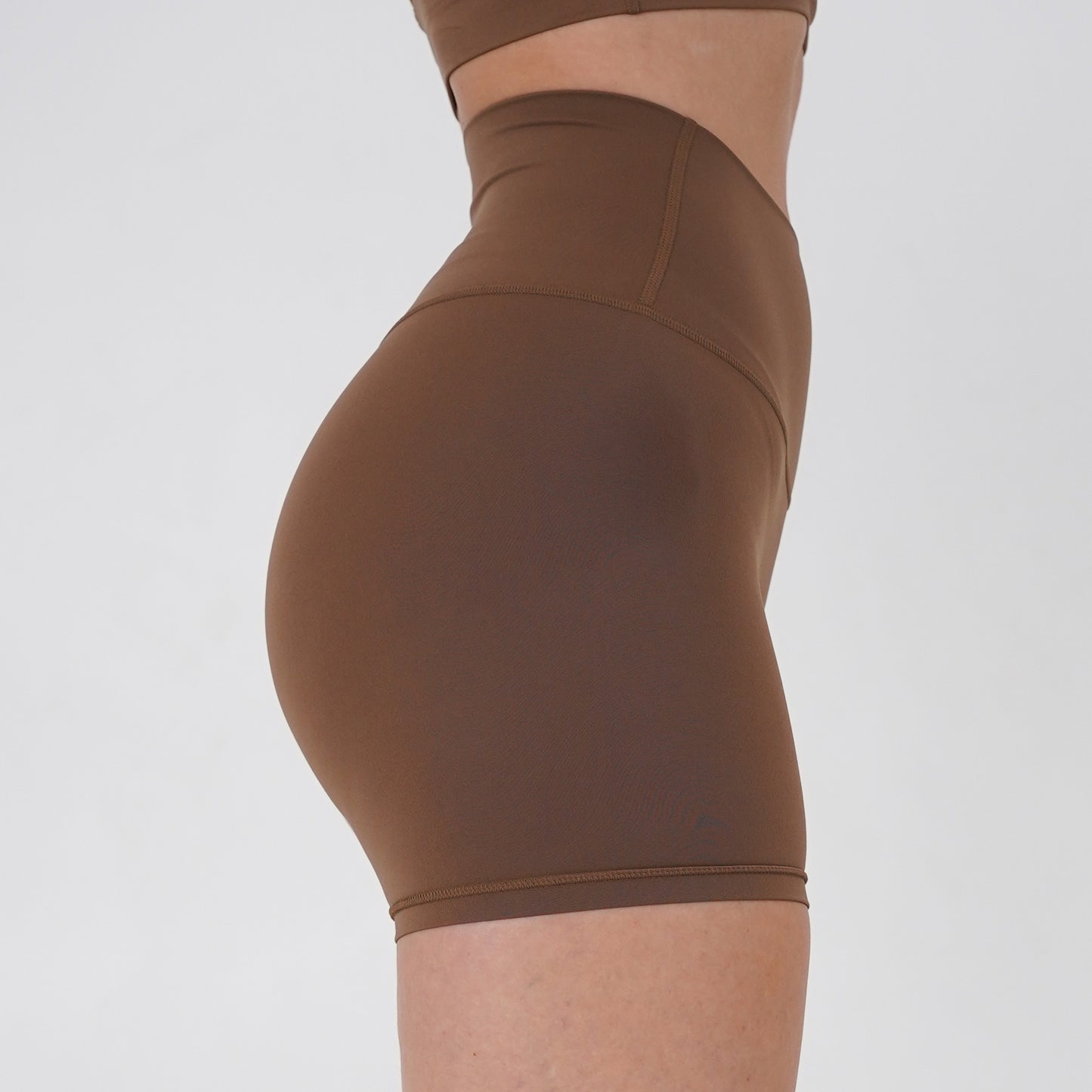 Pineapplebrat founder, influencer Alice Bozinovski, wears the Essential Shorts in Latte. Smooth comfort with our 5” inseam shorts—no front seam, high-rise design, and a blend of 80% nylon, 20% spandex for breathability and sculpting. Perfect for all-day wear.