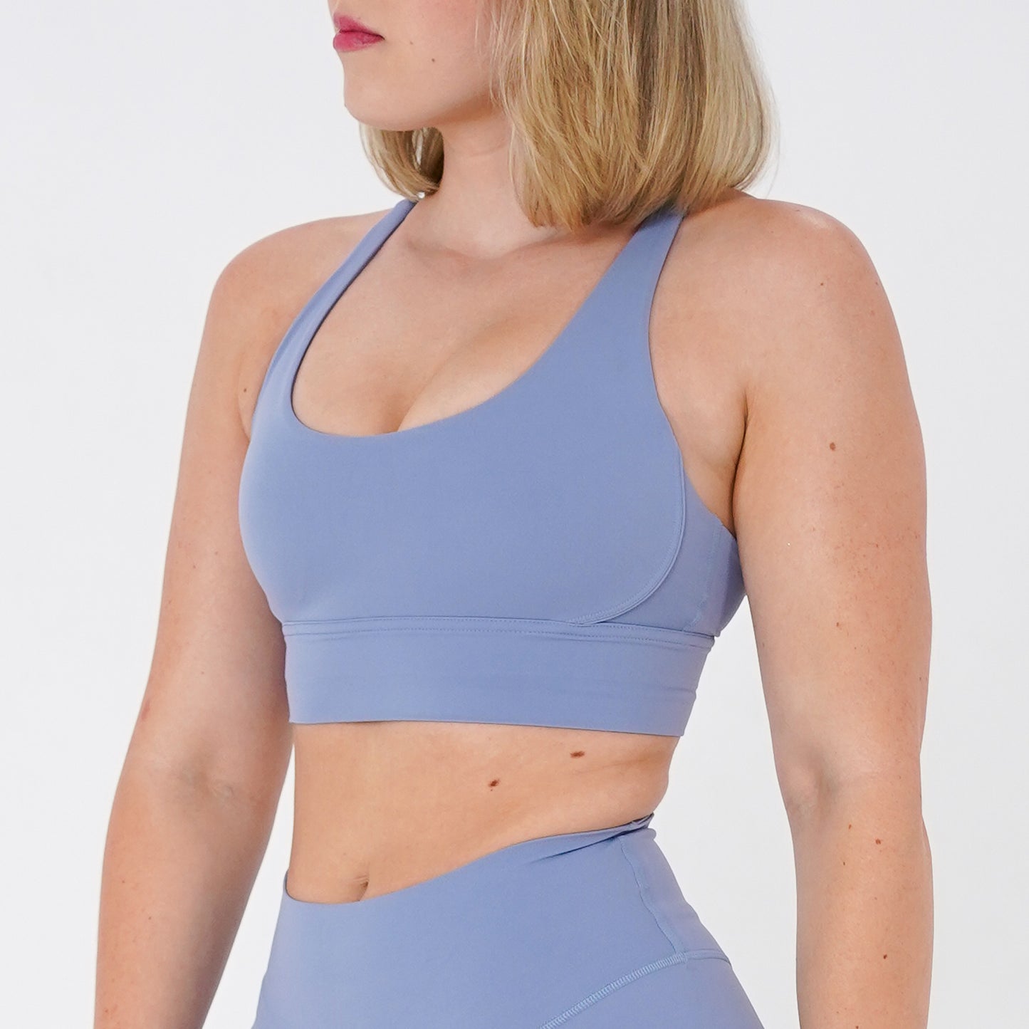 Pineapplebrat founder, influencer Alice Bozinovski, wears the Essential Sports Bra in Dusted Blue. Double-layered fabric, cross-back design, and durable under-bust band provide support in this activewear style. 80% nylon and 20% spandex with removable cups